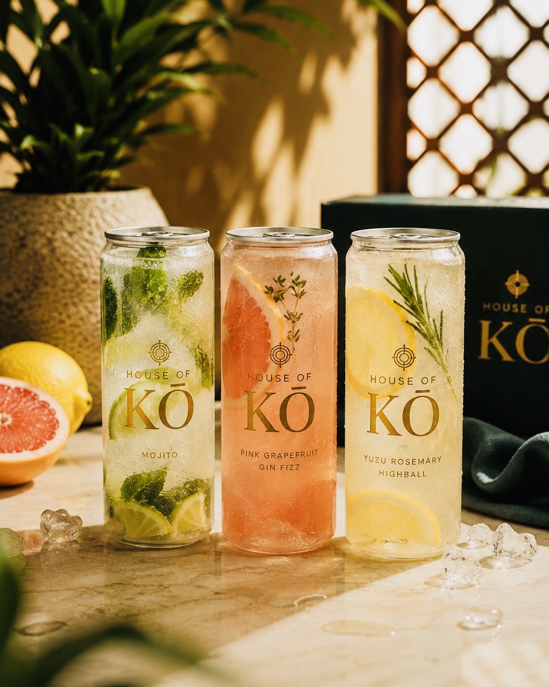 House of KŌ signature cocktail cans — Mojito, Pink Grapefruit Gin Fizz and Yuzu Rosemary Highball — with ice and citrus